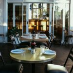 Sunlit restaurant interior with set tables and black chairs, one of the best restaurants in Guwahati.