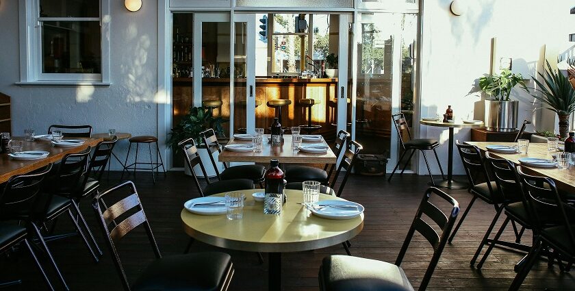 Sunlit restaurant interior with set tables and black chairs, one of the best restaurants in Guwahati.