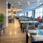 Spacious modern restaurant with wooden flooring, bright lighting, and diners near windows among the multiple restaurants in Havelock Island.