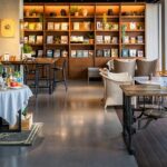 Wooden tables, chairs, and a bookshelf inside Ambient Café, a top spot for restaurants in Thimphu.