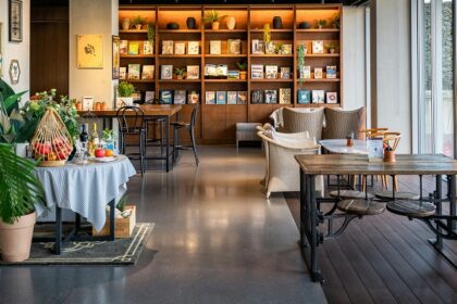 Wooden tables, chairs, and a bookshelf inside Ambient Café, a top spot for restaurants in Thimphu.