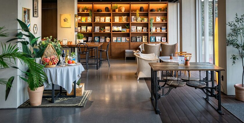 Wooden tables, chairs, and a bookshelf inside Ambient Café, a top spot for restaurants in Thimphu.