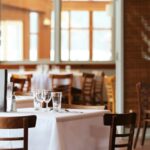 A dining room with tables set with white tablecloths and wooden chairs, one of the best South Indian Restaurants in Singapore.