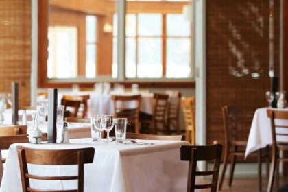 A dining room with tables set with white tablecloths and wooden chairs, one of the best South Indian Restaurants in Singapore.