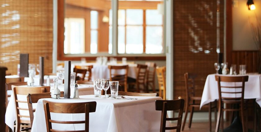 A dining room with tables set with white tablecloths and wooden chairs, one of the best South Indian Restaurants in Singapore.