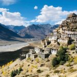 Fields and houses in Spiti Valley, Himachal Pradesh, under tall mountain ranges.