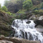 Waterfall cascading over rocky cliffs surrounded by lush greenery, one of the scenic waterfalls in Darjeeling.