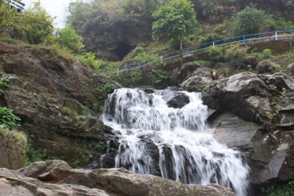 Waterfall cascading over rocky cliffs surrounded by lush greenery, one of the scenic waterfalls in Darjeeling.