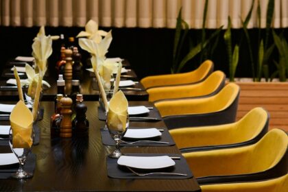 11th Avenue Café interior with long table, yellow chairs, and black cloth in one of the vibrant cafes in Jayanagar Guwahati.
