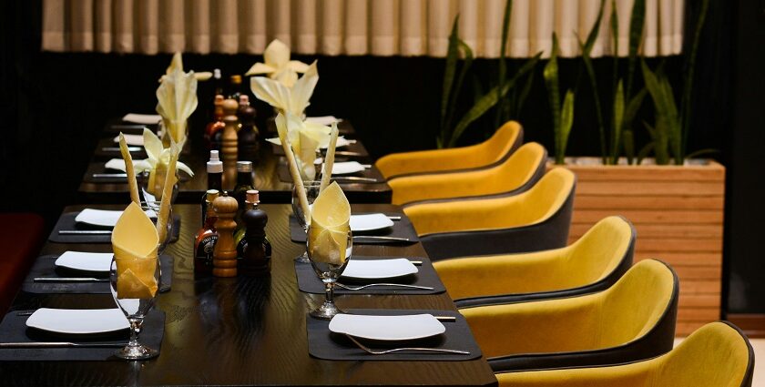 11th Avenue Café interior with long table, yellow chairs, and black cloth in one of the vibrant cafes in Jayanagar Guwahati.