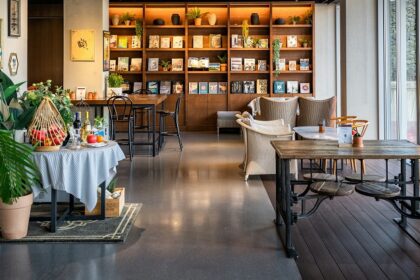 Cosy black coffee cafe interior with wooden furniture and a bookshelf, one of the trendy cafes in Zoo Road Guwahati.