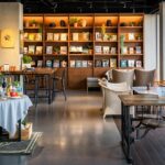 Salt & Pepper Bistro interior with tables, chairs, and wall-mounted bookshelf, one of the best couple restaurants in Dibrugarh.