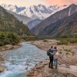 Couple enjoying a vacation at the scenic Baspa river valley with view of Himalaya mountain range in Himachal Pradesh