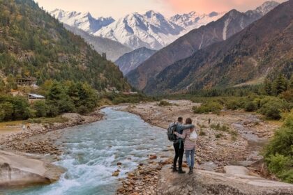 Couple enjoying a vacation at the scenic Baspa river valley with view of Himalaya mountain range in Himachal Pradesh