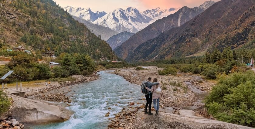 Couple enjoying a vacation at the scenic Baspa river valley with view of Himalaya mountain range in Himachal Pradesh