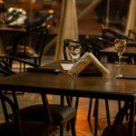 Dimly lit restaurant tables set with glasses and napkins, facing a street view at night, one of the best restaurants in Aizawl.