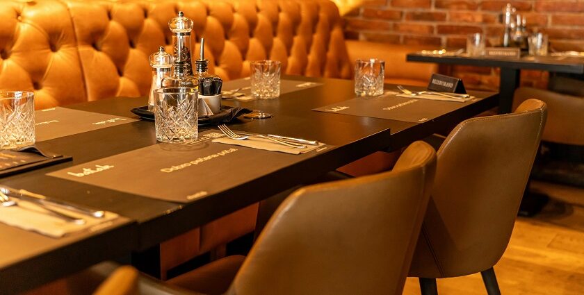 Warmly lit restaurant table with leather seating, glassware, and condiments neatly arranged, one of the restaurants in Jorhat.