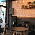 Interior of a restaurant with black tables, chairs, and light fixtures, one of the restaurants in Jowai.