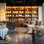Salt & Pepper Bistro interior with tables, chairs, and wall-mounted bookshelf, one of the best couple restaurants in Dibrugarh.