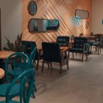 Blue Orchid restaurant interior with wooden accents, teal chairs, and warm ambient lighting, one of the top restaurants in Silchar.