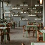 Piazza interior with white tables, chairs, and wall plants, one of the best restaurants in Ulubari Guwahati.