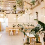 The Table Talk Cafe interior with white tables, chairs, and green plants, one of the best cafes in Uzan Bazar Guwahati.