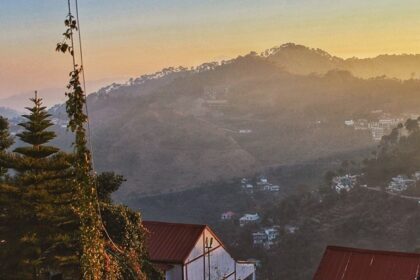 Snow-covered Kasauli hills are seen behind city buildings and telecom towers, showing snowfall in Kasauli.