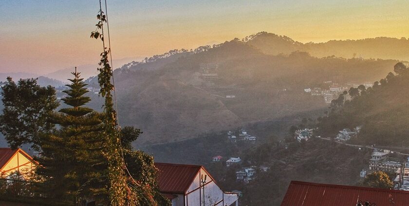 Snow-covered Kasauli hills are seen behind city buildings and telecom towers, showing snowfall in Kasauli.